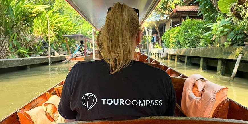 Nainen TourCompass t-paidassa istuu veneessä selkä kääntyneenä