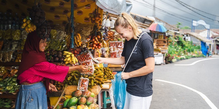 TourCompass-paitainen nainen maksaa naiselle tavaroista katukojussa.
