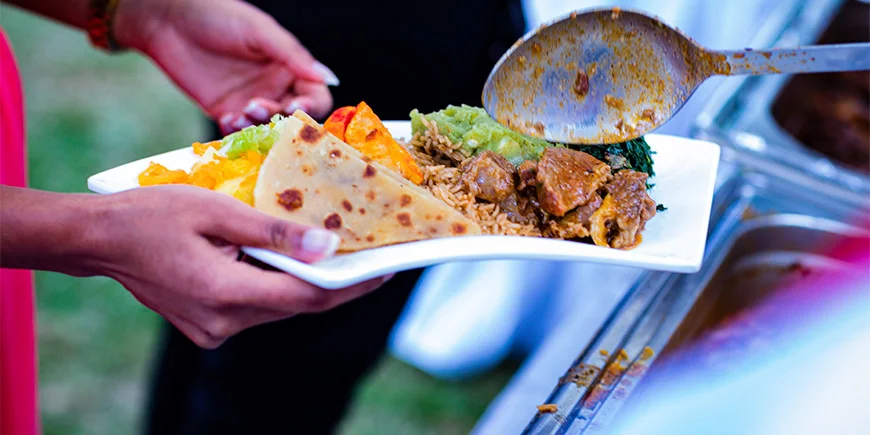 Nainen pitämässä lautasta, jossa on ruokaa Keniassa